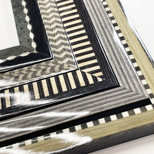 May include: Close-up of a multi-layered picture frame with a black, white, and gray geometric pattern. The frame is made of wood and has a glossy finish.