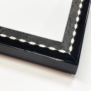 May include: Black picture frame with a white scalloped edge.