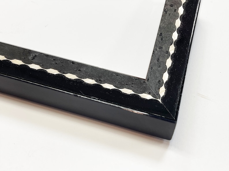 May include: Black picture frame with a white scalloped edge.