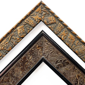 May include: Two decorative wooden picture frames. One frame is a light brown color with carved tiki masks and other designs. The other frame is dark brown with carved leaves and a black border. Both frames are angled.