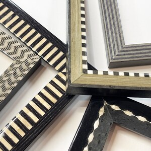 May include: Five different picture frames with black and white patterned borders. The frames are made of wood and have a variety of designs, including stripes, zigzags, and scallops.