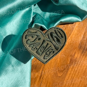 May include: A green heart-shaped patch with the word "Forever" embroidered in a stylized font.