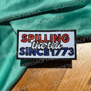 May include: White patch with red, white, and blue text that reads "SPILLING the tea SINCE 1773".