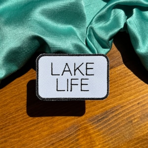 May include: White patch with black border and the text "LAKE LIFE" in black lettering.