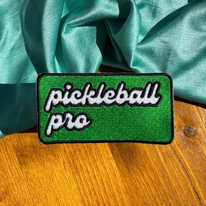May include: Green felt patch with white embroidered text that reads "pickleball pro".