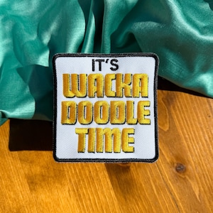 May include: White patch with black border and gold embroidered text that reads "It's Wacka Doodle Time".