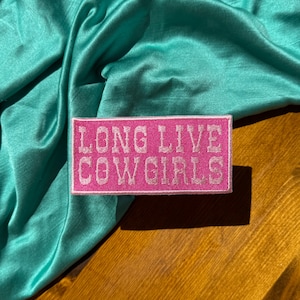 May include: Pink embroidered patch with white stitching that reads "Long Live Cowgirls".