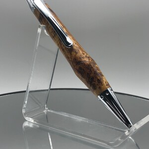 May include: A brown and silver pen with a wood grain pattern. The pen is on a clear acrylic stand.