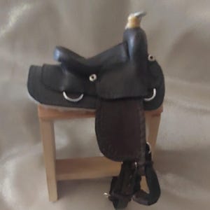 Sela tradicional western em escala 1:9 para cavalos Breyer ou Peter Stone. Couro marrom escuro com sturrips de couro e ferragens de metal.