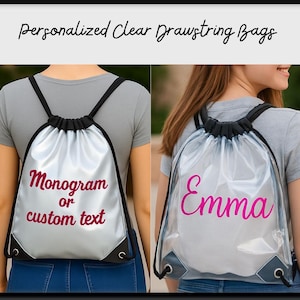 以下が含まれることがあります： 黒いストラップとトリムが付いた透明な巾着袋。片方のバッグにはマゼンタで「モノグラムまたはカスタムテキスト」というテキストがあり、もう片方のバッグにはマゼンタで「Emma」という名前があります。バッグはパーソナライズされています。