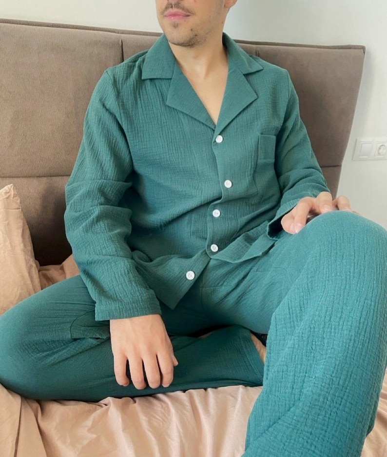 K&ouml;nnte beinhalten: Ein gr&uuml;ner Schlafanzug mit einem Hemd mit Kragen und einer langen Hose. Das Hemd hat einen Knopfleisten vorne und eine Tasche auf der linken Seite.