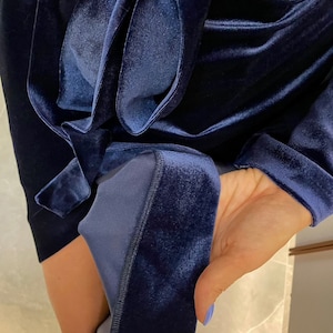 May include: A navy blue velvet robe with a long sleeve and a sash tie. The robe is made of a soft, luxurious fabric.