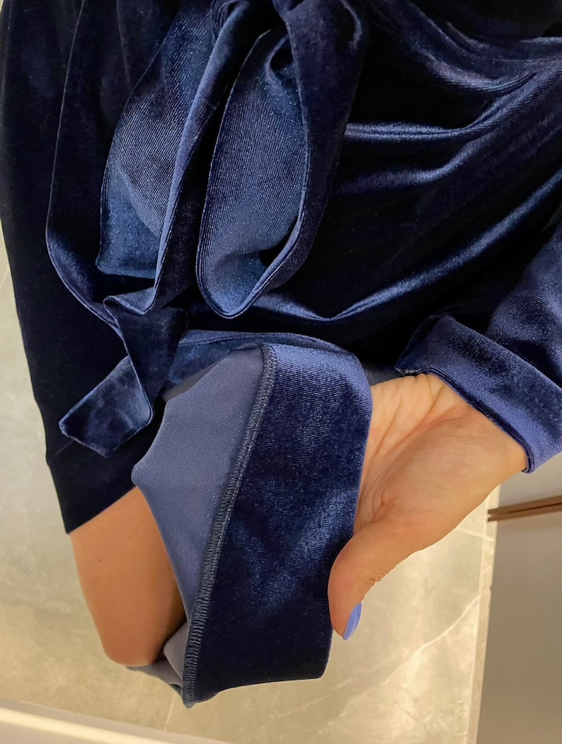 May include: A navy blue velvet robe with a long sleeve and a sash tie. The robe is made of a soft, luxurious fabric.