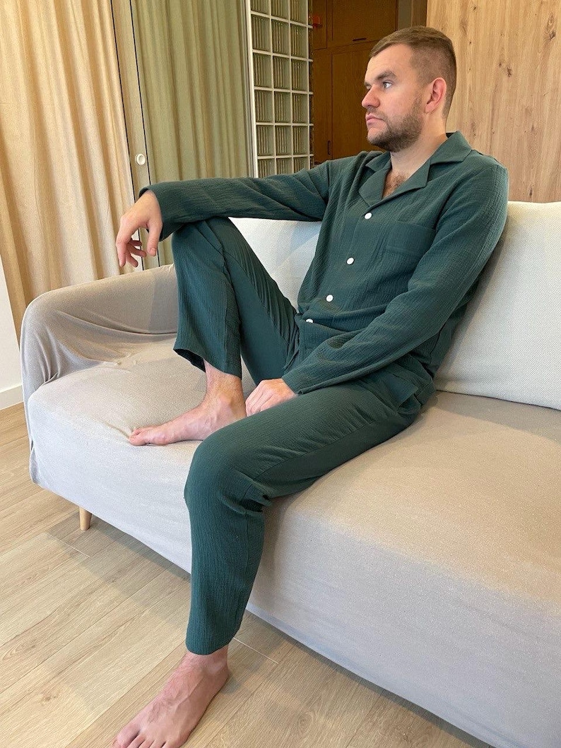 K&ouml;nnte beinhalten: Eine Person tr&auml;gt einen dunkelgr&uuml;nen, lang&auml;rmeligen Schlafanzug-Oberteil und eine passende Hose. Der Schlafanzug hat einen Knopfleistenverschluss und einen Kragen.