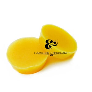 May include: Two round, yellow beeswax blocks, one on top of the other. The top block has the text "L'AVALLER & BOUCARA" printed on it.