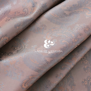 May include: A close-up of a brown fabric with a paisley pattern. The fabric has a subtle sheen and a soft texture.