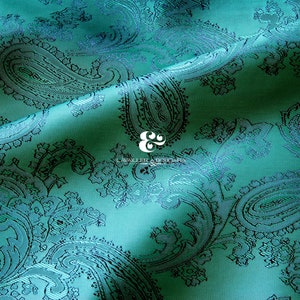 May include: Teal paisley fabric with a subtle sheen. The fabric has a repeating pattern of paisley shapes in a darker shade of teal.