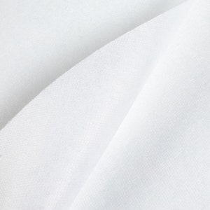 May include: White fabric with a smooth, textured surface. The fabric is folded in half, creating a diagonal crease.