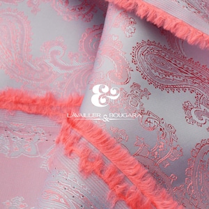 May include: Close-up of a fabric with a paisley pattern in shades of pink and gray. The fabric has a fringed edge in a bright coral color. The text "LAVAILLER & BOUGARA" is visible.