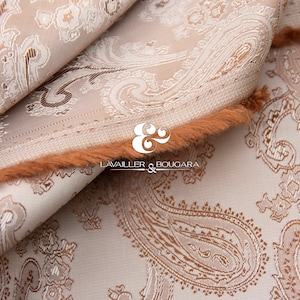 May include: Close-up of a beige fabric with a brown paisley pattern. The fabric has a fuzzy brown trim. The text "LAVAILLEUR & BOUGARA" is visible in the image.