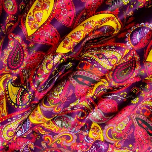 Puede incluir: Primer plano de una tela morada con un patrón paisley en tonos amarillos, rosas y rojos.