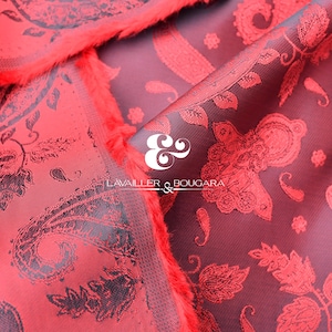 Puede incluir: Primer plano de tela roja con un estampado de cachemira en un tono rojo más oscuro. La tela tiene una apariencia texturizada y un borde con flecos. También se muestra el logotipo "LAVAILLER & BOUGARA".
