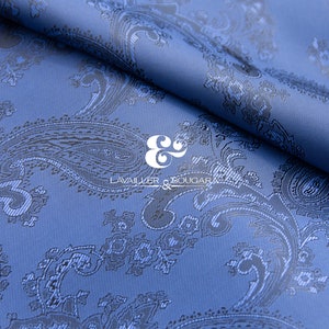 Pode incluir: Tecido azul com padrão paisley e um logotipo preto e branco que diz "LAVALIER & BOUGAR" no centro.