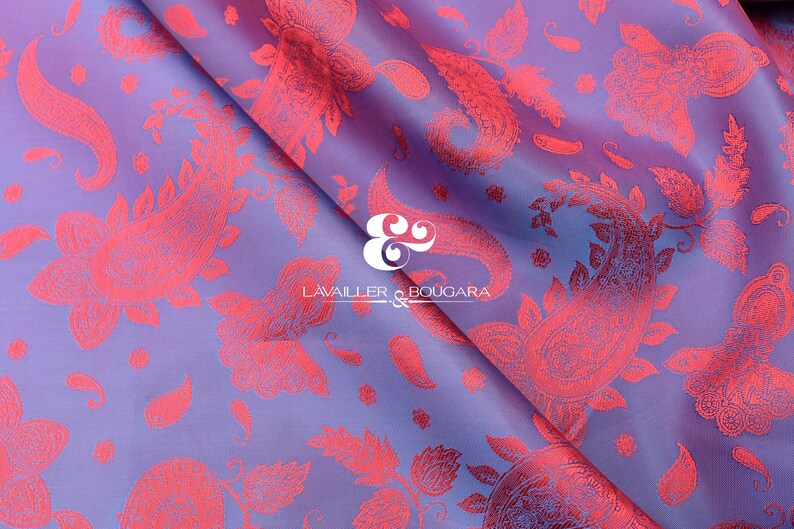 Puede incluir: Una tela doblada con un patr&oacute;n de cachemira coral repetido sobre un fondo lavanda y azul. La tela tiene brillo y los dise&ntilde;os de cachemira son detallados. La marca "LAVALLER & BOUGARA" es visible.