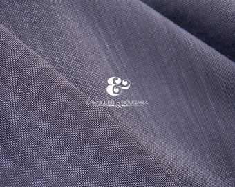 Puede incluir: Primer plano de una tela gris oscuro con una textura sutil. La tela está doblada de forma que crea una línea diagonal. La tela tiene un logotipo blanco con el texto "Lawler & Bougara" en una fuente cursiva.