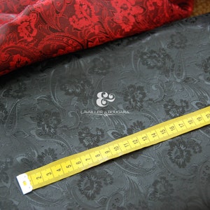 May include: Black and red paisley patterned fabric with a yellow measuring tape. The tape reads "LAVAILLER BOUDARA" and measures up to 25 inches.