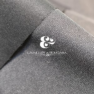 May include: Close-up of a dark gray fabric with a textured surface. The fabric is folded, revealing a layered effect. The logo "LAVAILLER & BOUGARA" is visible in white.