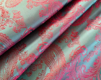 Könnte beinhalten: Tealfarbener Stoff mit rotem Paisley-Muster. Der Stoff ist in der Mitte gefaltet und zeigt das Muster auf beiden Seiten.