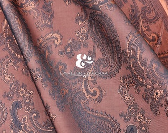 May include: A close-up of a brown fabric with a paisley pattern. The fabric has a subtle sheen and a soft texture. The text "LAVAILLEUR & BOUCARA" is printed in white on the fabric.
