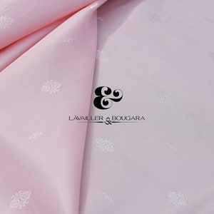 May include: A pale pink fabric with a subtle white floral pattern. The fabric is folded in half and the text "L'AVAILLER & BOUGARA" is visible in the center of the image.