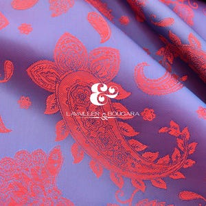 May include: Close-up of a purple fabric with a red paisley pattern. The fabric has a satin sheen and is folded, creating shadows and highlights. The text "LAVAILLER & BOUGARA" is visible.