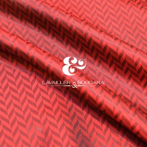 Pode incluir: Tecido vermelho com um padrão de espinha de peixe vermelho escuro. O tecido está drapeado, mostrando dobras e sombras. A marca "LAVAILLER & BOUGARA" é exibida em branco.