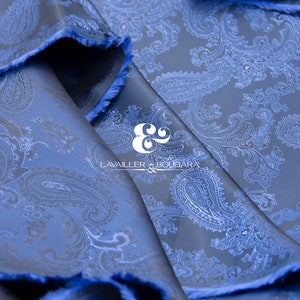 May include: Blue paisley patterned fabric with a white paisley design. The fabric is folded and the edges are frayed. The text "LAVAILLEUR & BOUJARA" is visible in the center of the image.