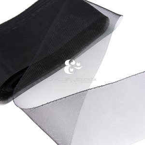 Könnte beinhalten: Schwarzes Tüllband mit gekräuselter Textur. Das Band ist in der Mitte gefaltet und die Kanten sind ausgefranst.