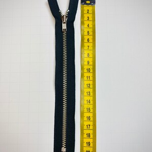 May include: A black zipper with a silver slider, measuring 22 inches long.
