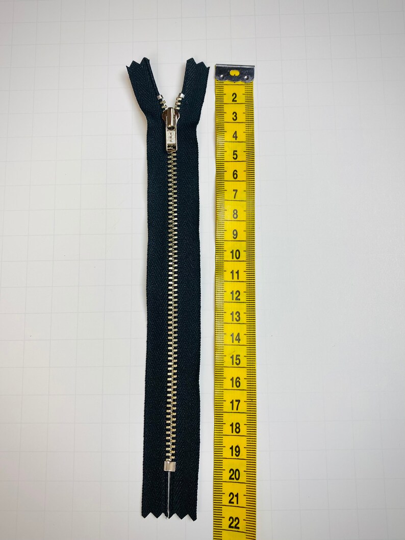 May include: A black zipper with a silver slider, measuring 22 inches long.