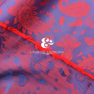 Puede incluir: Primer plano de una tela con un estampado de cachemir en tonos morados, rojos y azules. La tela tiene un aspecto texturizado y un borde con flecos. El texto "LAVALLER & BOUGARA" es visible.