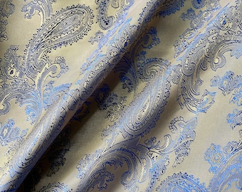 May include: A beige fabric with a blue and gold paisley pattern. The fabric is folded in half, showing the pattern on both sides.