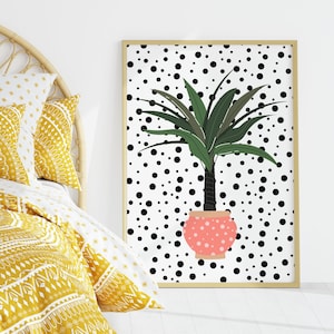 Pode incluir: Uma capa de edredom com padrão amarelo e branco com uma almofada combinando em uma cama com cabeceira de vime. Uma impressão emoldurada de uma planta verde em um vaso rosa sobre um fundo branco com bolinhas pretas pendura na parede.