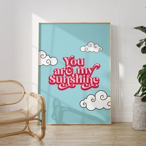May include: A blue and white poster with the text "You are my Sunshine" in pink and red letters. The poster is framed in gold and has white clouds on a blue background.
