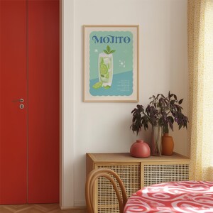 May include: A framed poster with the word "MOJITO" in blue lettering. The poster features a stylized illustration of a mojito cocktail with lime slices and mint leaves. The background is light blue and white.