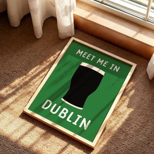 May include: A framed green sign with the words "MEET ME IN DUBLIN" in white lettering. A black pint of stout is in the center of the sign. The frame is a light wood color. The sign is on a brown carpet.
