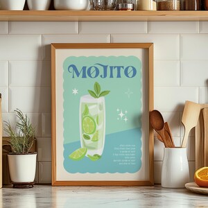 May include: A framed print featuring a Mojito cocktail illustration. The artwork showcases a tall glass filled with lime slices, mint, and ice, with the word "Mojito" in blue script. The background is a light blue with decorative stars.