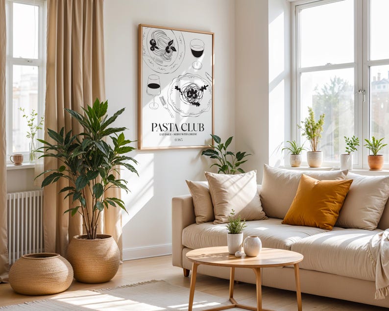 K&ouml;nnte beinhalten: Ein helles, luftiges Wohnzimmer mit beigem Sofa, rundem Holztisch und gro&szlig;en Topfpflanzen. Ein gerahmter "Pasta Club"-Druck h&auml;ngt an der Wand. Der Raum ist mit nat&uuml;rlichem Licht von einem gro&szlig;en Fenster gef&uuml;llt.