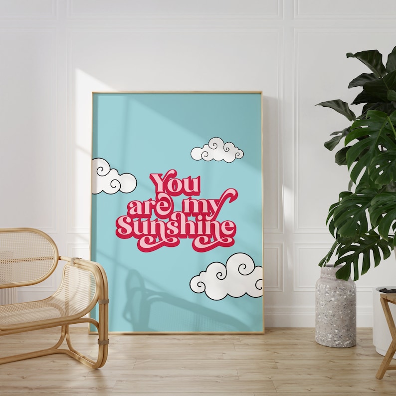 May include: A blue and white poster with the text "You are my Sunshine" in pink and red letters. The poster is framed in gold and has white clouds on a blue background.