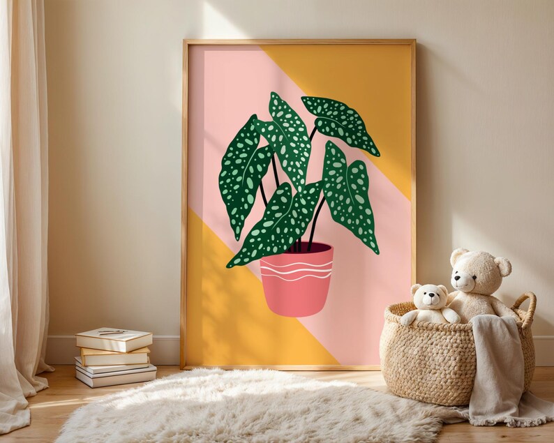 May include: A framed art print depicting a stylized illustration of a potted plant with large green leaves dotted with white spots. The plant is in a pink pot with a white wavy design, set against a pink and yellow geometric background.